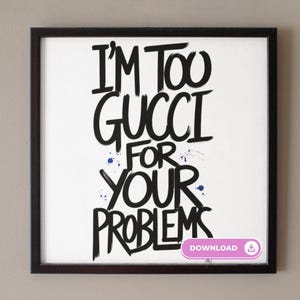 May include: Black and white framed print with the text "I'm too gucci for your problems" in a graffiti style font. Blue paint splatters are visible on the white background.