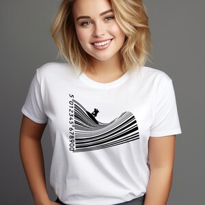 Può includere: T-shirt bianco con grafica in bianco e nero di un surfista su un'onda formata da linee di codice a barre. Il design del codice a barre include i numeri 5012345678900. La maglietta è a girocollo classico.