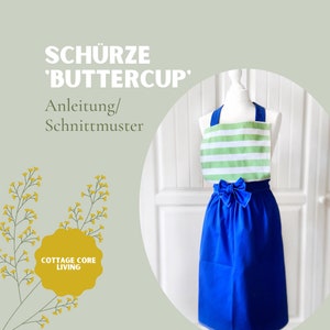 Può includere: Un grembiule a righe blu e bianche con una parte superiore a righe verdi e bianche e un fiocco blu. Il grembiule è su un manichino bianco. Il testo "Schürze 'Buttercup' Anleitung/Schnittmuster" è nella parte superiore dell'immagine. Il testo "Cottage Core Living" è in un cerchio giallo nella parte inferiore dell'immagine.