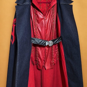 May include: A red and black costume with a denim cape. The costume includes a red hooded top with a zip, a black belt with a silver buckle, and a long red skirt. The denim cape has a red design on the sleeve.