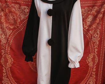 May include: A black and white clown costume with a ruffled collar and pom-pom buttons. The long-sleeved outfit is split vertically, with one side black and the other white. The costume is displayed on a mannequin.