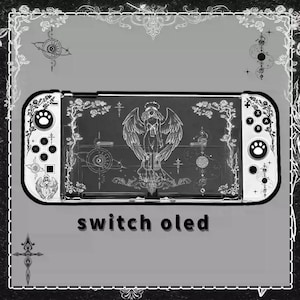 Może przedstawiać: Czarno-biała konsola Nintendo Switch OLED z niestandardowym wzorem przedstawiającym anioła z skrzydłami i wzorami kwiatowymi. Tekst "switch oled" jest nadrukowany pod konsolą.