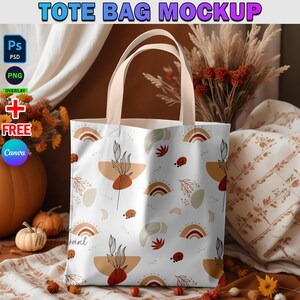 May include: White tote bag mockup with a colorful abstract pattern featuring rainbows, leaves, and ladybugs. The bag is sitting on a brown surface with fall decor.