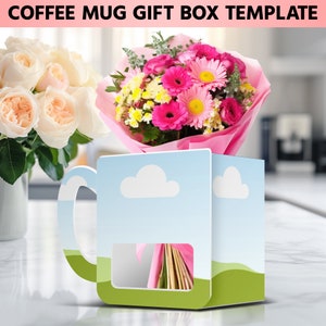 Puede incluir: Una plantilla de caja de regalo de taza de caf&eacute; azul y verde con una ventana recortada para mostrar un ramo de flores rosas y blancas. La caja tiene un dise&ntilde;o de nube y el texto "COFFEE MUG GIFT BOX TEMPLATE" en la parte superior.