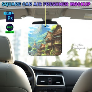 May include: A square car air freshener mockup with a colorful image of a fantasy village with a mountain in the background. The air freshener is hanging from the rearview mirror of a car.