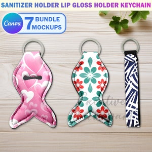 May include: Three keychains with different designs. The first keychain is pink with a heart pattern and a small opening for a bottle of hand sanitizer. The second keychain is white with a green and red floral pattern. The third keychain is blue and white with a geometric pattern. All three keychains are on a wooden surface.