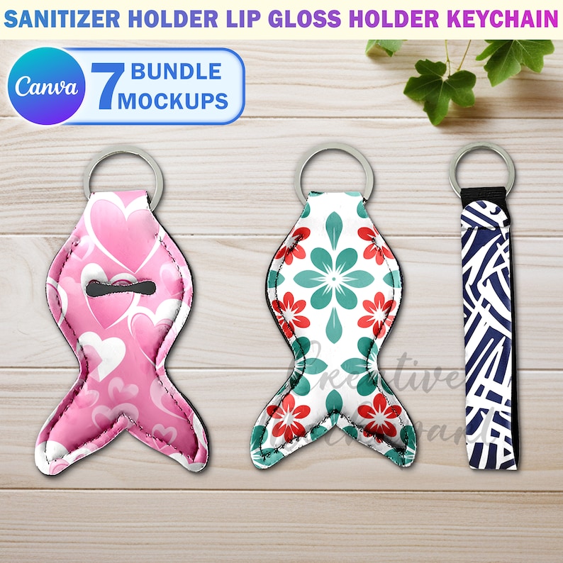 May include: Three keychains with different designs. The first keychain is pink with a heart pattern and a small opening for a bottle of hand sanitizer. The second keychain is white with a green and red floral pattern. The third keychain is blue and white with a geometric pattern. All three keychains are on a wooden surface.