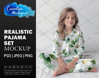May include: A white pajama set with a floral print featuring green leaves and white flowers. The model is wearing the pajama set and sitting on a white bed.