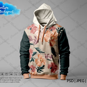 Puede incluir: Una sudadera con capucha beige con estampado floral y mangas verde oscuro. La sudadera tiene capucha con cordón y bolsillo canguro.