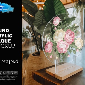 May include: A round clear acrylic plaque with a floral design featuring pink and white roses. The plaque is on a wooden stand.