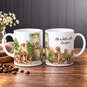 Könnte beinhalten: Zwei weiße Keramiktassen mit Illustrationen von goldbraunen Cavapoo-Hunden in einem Garten. Eine Tasse zeigt Hunde bei einem Zitronenbaum und Efeu, die andere einen Hund an einem Zaun mit dem Text, Life is better with a Cavapoo.