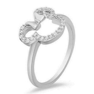 Puede incluir: Un anillo de plata con un lazo de cristal transparente y un contorno de cabeza de Mickey Mouse. El anillo est&aacute; engastado con peque&ntilde;os cristales transparentes.