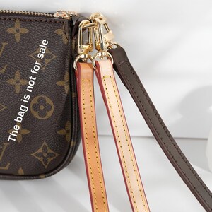 May include: A brown handbag with a monogram pattern and gold-tone hardware. The bag has three detachable straps in tan, pink, and dark brown. The text "The bag is not for sale" is visible on the bag.