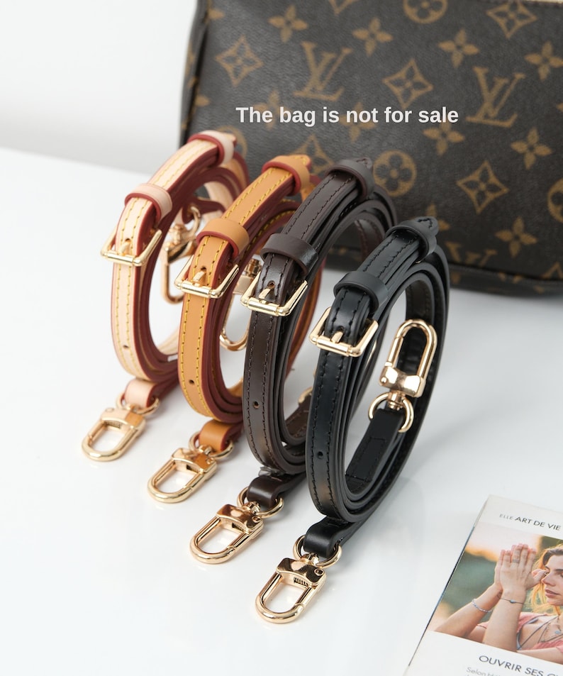 May include: Four leather purse straps in cream, tan, dark brown, and black. Each strap has a gold-coloured buckle and clasp. The bag in the background is not for sale.