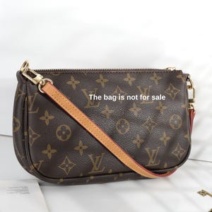 May include: Brown monogrammed handbag with a tan leather strap and gold-tone hardware. The bag features a repeating pattern of interlocking logos and floral designs. The text "The bag is not for sale" is visible on the bag.