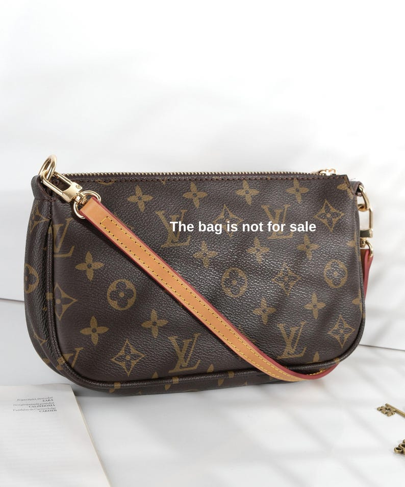 May include: Brown monogrammed handbag with a tan leather strap and gold-tone hardware. The bag features a repeating pattern of interlocking logos and floral designs. The text "The bag is not for sale" is visible on the bag.