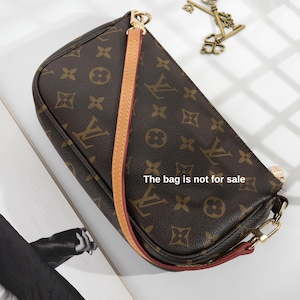 May include: Brown handbag with a repeating pattern and a tan strap. The bag has gold-colored hardware and a red trim. The text "The bag is not for sale" is visible on the bag.
