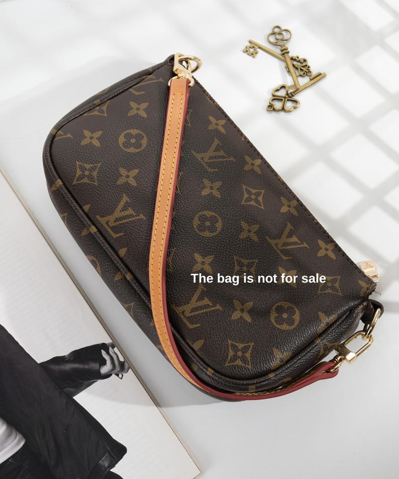 May include: Brown handbag with a repeating pattern and a tan strap. The bag has gold-colored hardware and a red trim. The text "The bag is not for sale" is visible on the bag.