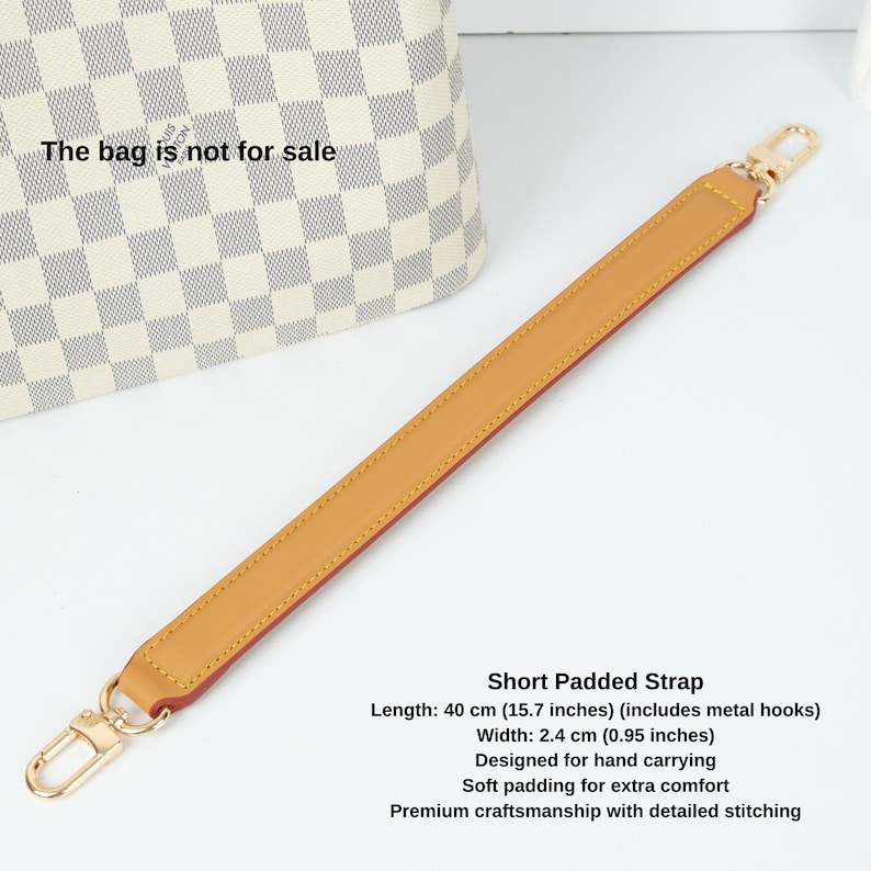 May include: A short padded strap with gold metal hooks. The strap is 40 cm (15.7 inches) long and 2.4 cm (0.95 inches) wide. It is designed for hand carrying and has soft padding for extra comfort. The strap features premium craftsmanship with detailed stitching.