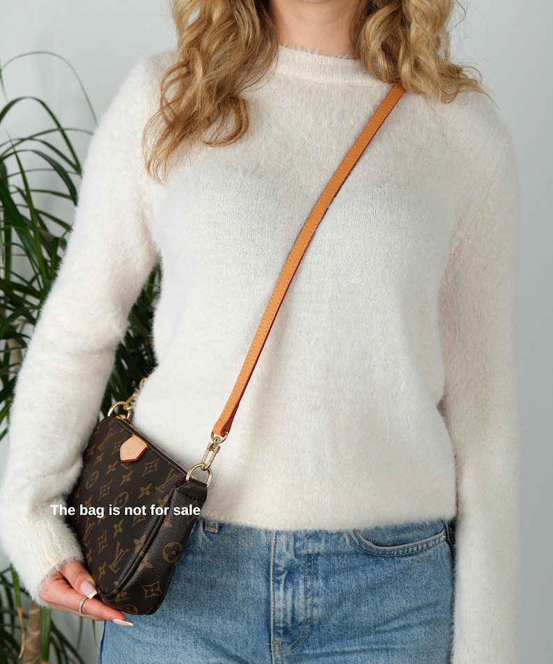 May include: Brown and tan crossbody bag with a gold chain and a tan leather strap. The bag features a repeating pattern of brown logos. The text "The bag is not for sale" is visible on the image.