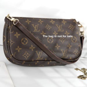May include: Brown handbag with a repeating pattern of logos and symbols. The bag has a brown strap and gold-colored hardware. The text "The bag is not for sale" is printed on the bag.