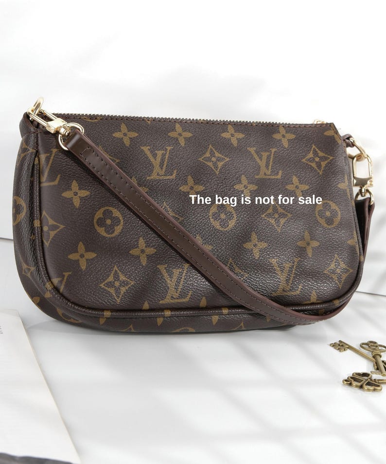 May include: Brown handbag with a repeating pattern of logos and symbols. The bag has a brown strap and gold-colored hardware. The text "The bag is not for sale" is printed on the bag.