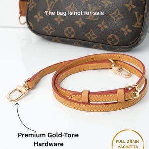 May include: A brown handbag with a repeating pattern and a separate tan leather strap with gold-tone hardware. The strap is made of full-grain vachetta leather. The bag is not for sale.