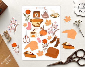 Op de afbeelding: Een vel vinyl stickerpapier met herfstthema illustraties. De stickers bevatten een theepot, een pompoen, bladeren, sokken, een trui, een taart en een deegroller. De tekst "Five O'Clock Art" staat in de rechterbovenhoek van het vel.