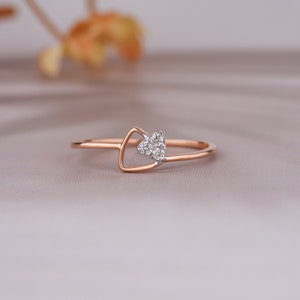 May include: A rose gold ring with a triangular design. The ring features a small triangle of white gemstones set within a larger open triangle. The band is thin and delicate, suitable for everyday wear.