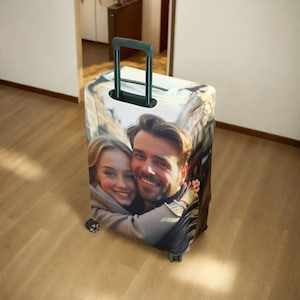 May include: A luggage cover with a photo of a couple smiling and hugging. The cover is white with a black handle.