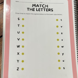 May include: A spiral-bound workbook page with the title "MATCH THE LETTERS." The page features capital letters on the left and lowercase letters on the right, with yellow dots for matching. The workbook has a pink border.