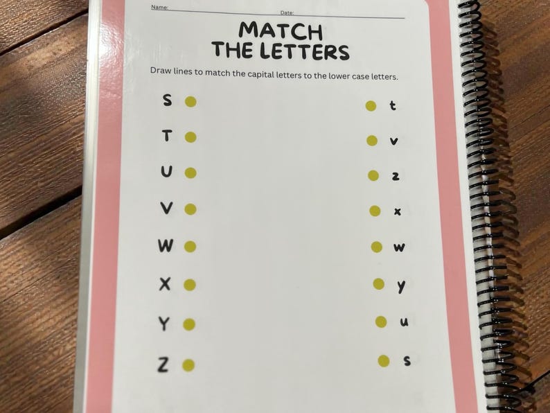 May include: A spiral-bound workbook page with the title "MATCH THE LETTERS." The page features capital letters on the left and lowercase letters on the right, with yellow dots for matching. The workbook has a pink border.