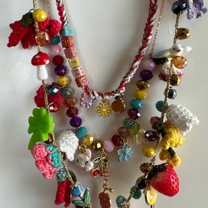 May include: Multi-strand necklace with a variety of colorful beads, charms, and crocheted flowers. The necklace features a charm with the word "SPRING" spelled out in colorful blocks.