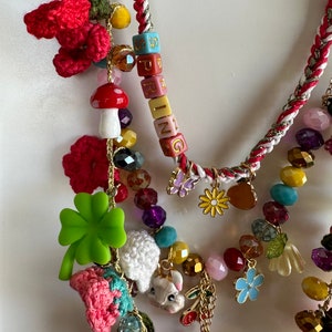 May include: Multi-strand necklace with colorful beads, charms, and crocheted flowers. The necklace features a charm with the word "SPRING" spelled out in colorful blocks.