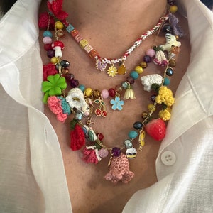 May include: A multi-layered necklace with colorful beads, charms, and crocheted flowers. The necklace features a charm with the word "SPRING" spelled out in colorful letters.