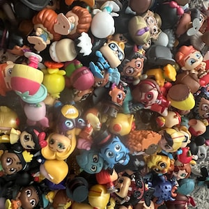 May include: A collection of small, colorful figurines, featuring various characters with distinct designs. The figurines are in a variety of colors, including yellow, blue, red, and brown. The collection appears to be a mix of different characters.
