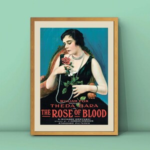 Pode incluir: Um cartaz de filme vintage anunciando o filme "The Rose of Blood" estrelado por Theda Bara. O cartaz apresenta uma mulher com um vestido preto segurando uma rosa vermelha, com o texto do título em vermelho e branco.