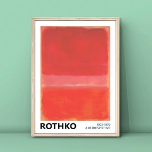 May include: A framed print of an abstract painting by Mark Rothko. The painting features three horizontal bands of red, pink, and orange. The print includes the artist's name, "Rothko", and the dates "1903-1970" and "A Retrospective".