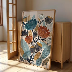 May include: A rectangular framed wall art print featuring a botanical illustration of stylized flowers and leaves in shades of teal, burnt orange, mustard yellow, and dark blue against a cream background, enclosed in a light wood frame.