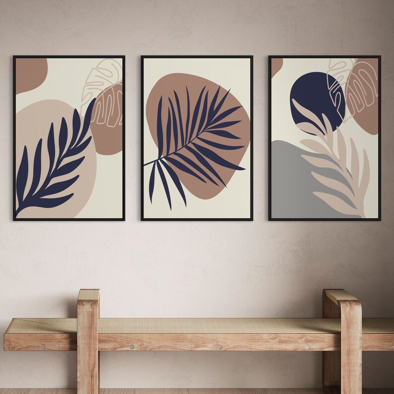 May include: Three framed prints with abstract designs featuring brown, beige, and blue colours. Each print features a stylised leaf design with a minimalist aesthetic.