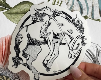 May include: Black and white line art sticker of a cowboy riding a bucking bronco. The sticker is round and has the text "Yee-Haw" at the bottom.