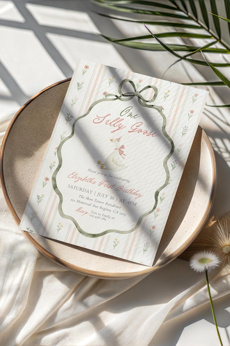 May include: A whimsical invitation for a first birthday celebration. The design features a watercolor illustration of a goose wearing a party hat, with the text "One Silly Goose." The invitation is set on a striped background with floral accents.