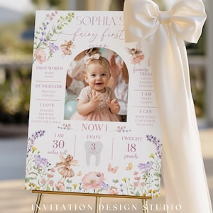 May include: A personalized first birthday sign featuring a photo of a baby girl. The sign includes the text "Sophia's fairy first year" with details like height (30 inches), weight (18 pounds), and favorite things. The sign is decorated with floral and fairy illustrations.