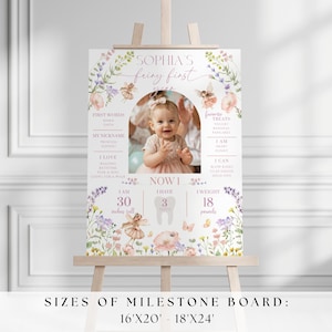 May include: A milestone board on an easel, featuring a photo of a baby girl. The board is decorated with floral and fairy illustrations, and includes the text "Sophia's fairy first year." The board also includes the baby's height of 30 inches and weight of 18 pounds.