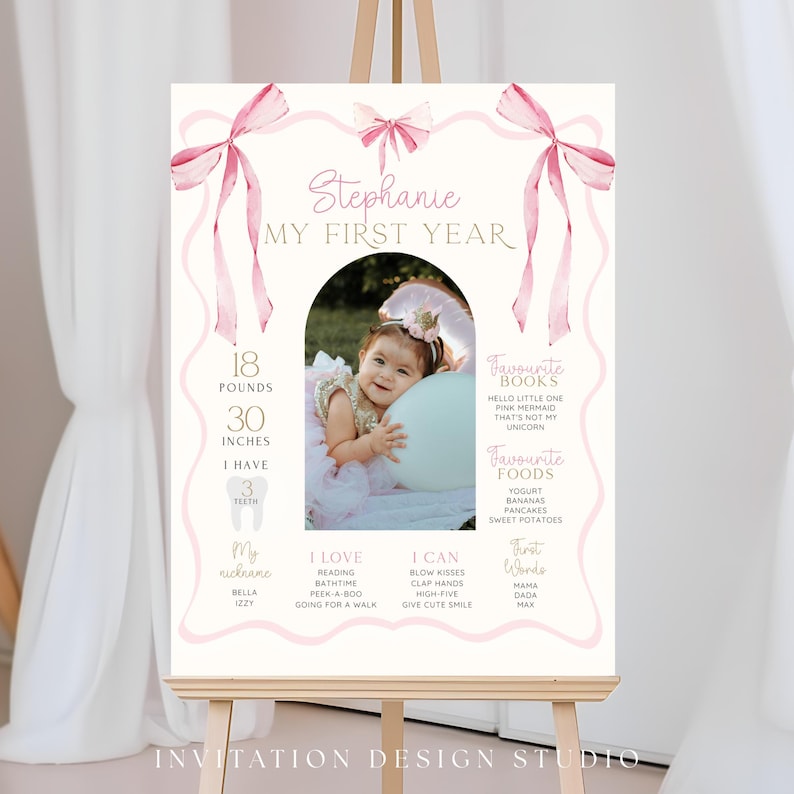 May include: A personalized first birthday sign on an easel. The sign features a photo of a baby girl, pink bows, and text including the baby's name, measurements (18 pounds, 30 inches), and favorite things.