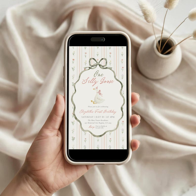 May include: A smartphone displays a digital invitation with the text "One Silly Goose" and details for a first birthday celebration. The design features a goose illustration, a bow, and a floral background.