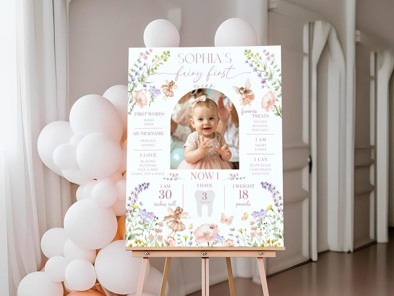 May include: A personalized first birthday sign featuring a photo of a baby girl. The sign includes the text "Sophia's Fairy First" with floral and fairy illustrations. The sign indicates the baby is 30 inches tall and weighs 18 pounds.