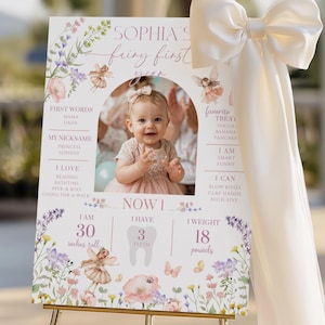 Pode incluir: Um letreiro personalizado para o primeiro anivers&aacute;rio, com uma foto de uma menina. O letreiro inclui o texto "Sophia's Fairy First Year" com ilustra&ccedil;&otilde;es florais e de fadas. O beb&eacute; mede 76 cm e pesa 8,2 kg.