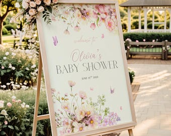 Może przedstawiać: Drewniany sztalug stoi z tablicą z ilustracjami kwiatów i motyli. Na tablicy widnieje napis "welcome to Olivia's BABY SHOWER June 15th 2025". Tablica jest ozdobiona różowymi i fioletowymi kwiatami i motylami. Bukiet różowych róż zdobi górę.