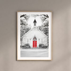 K&ouml;nnte beinhalten: Ein Schwarzwei&szlig;foto einer kleinen wei&szlig;en Kirche mit einer roten T&uuml;r. Die Kirche ist mit Schnee bedeckt und die B&auml;ume um sie herum sind kahl. Die Kirche ist in einem Holzrahmen gerahmt.